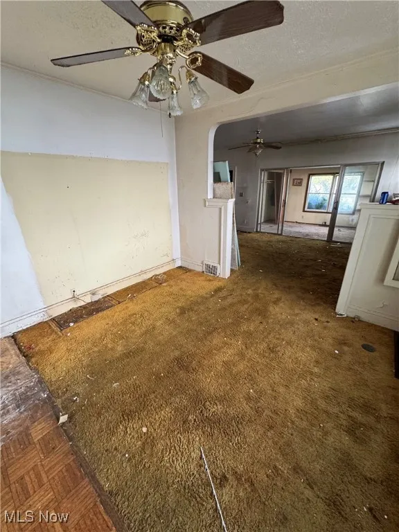 Unfurnished living room with a textured ceiling and baseboards