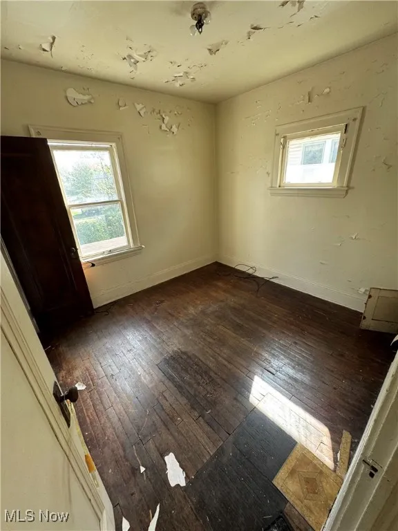 Unfurnished bedroom featuring baseboards and dark wood-style floors