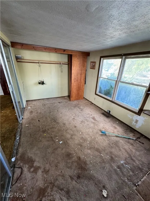 Unfurnished bedroom with a closet, a textured ceiling, and carpet