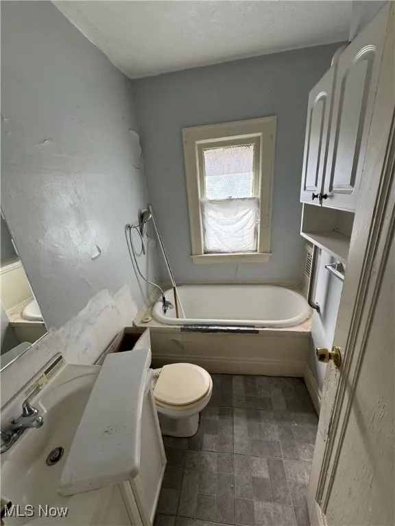 Bathroom featuring a garden tub, vanity, and a textured ceiling