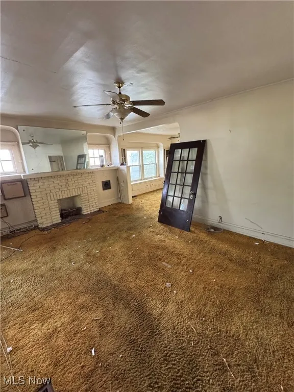 Unfurnished living room with carpet and ceiling fan