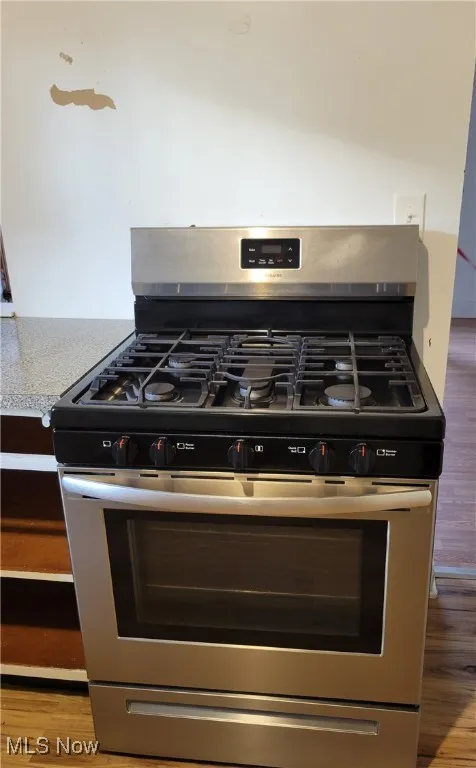 Kitchen view of light wood-style floors, stainless steel range with gas cooktop, and light countertops