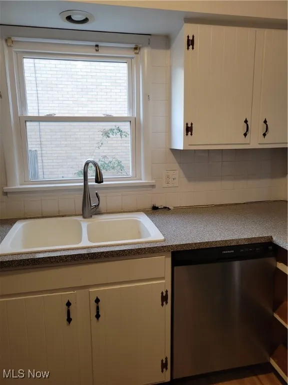 Kitchen featuring dishwasher, white cabinets, decorative backsplash, and light countertops