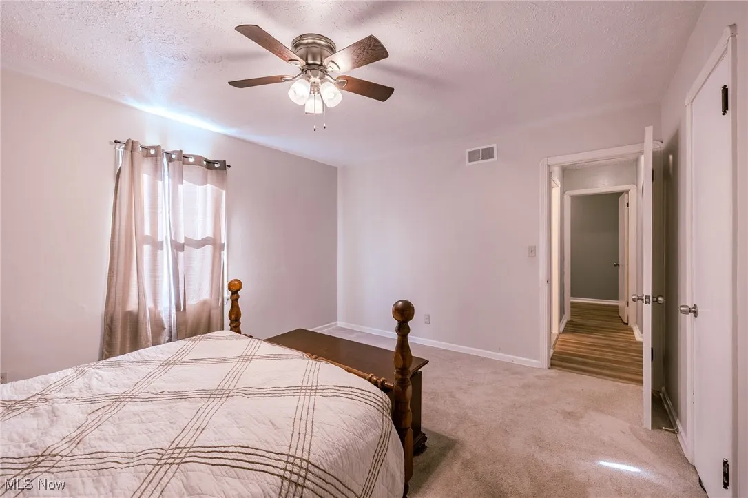 Bedroom with a textured ceiling, carpet floors, and a ceiling fan
