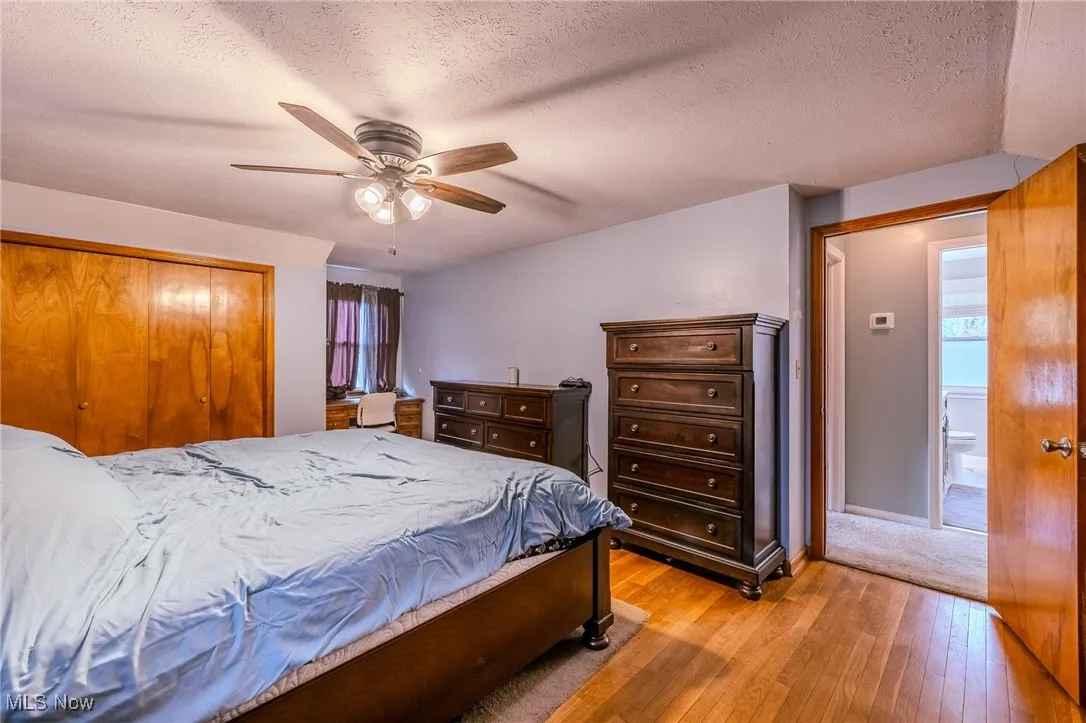Bedroom featuring a textured ceiling, light wood-style floors, a closet, and a ceiling fan