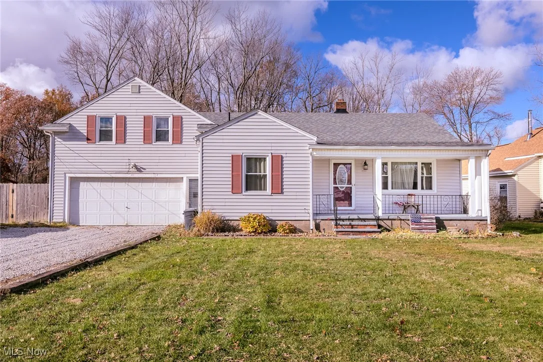 View of front of property with covered porch, driveway, roof with shingles, a chimney, and an attached garage