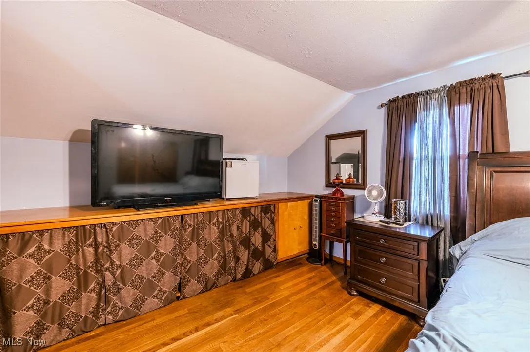 Bedroom featuring hardwood / wood-style flooring, vaulted ceiling, and a textured ceiling