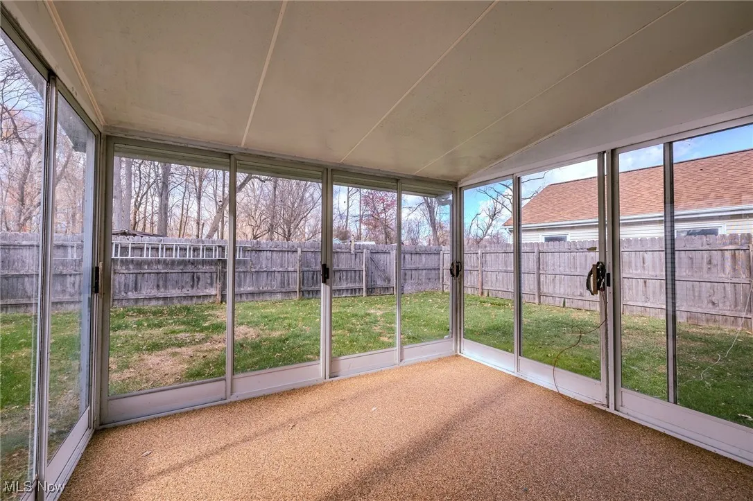 Unfurnished sunroom with healthy amount of natural light and vaulted ceiling