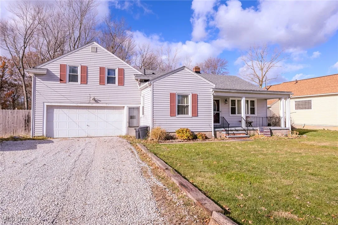 View of front of house featuring a porch, gravel driveway, an attached garage, and a shingled roof