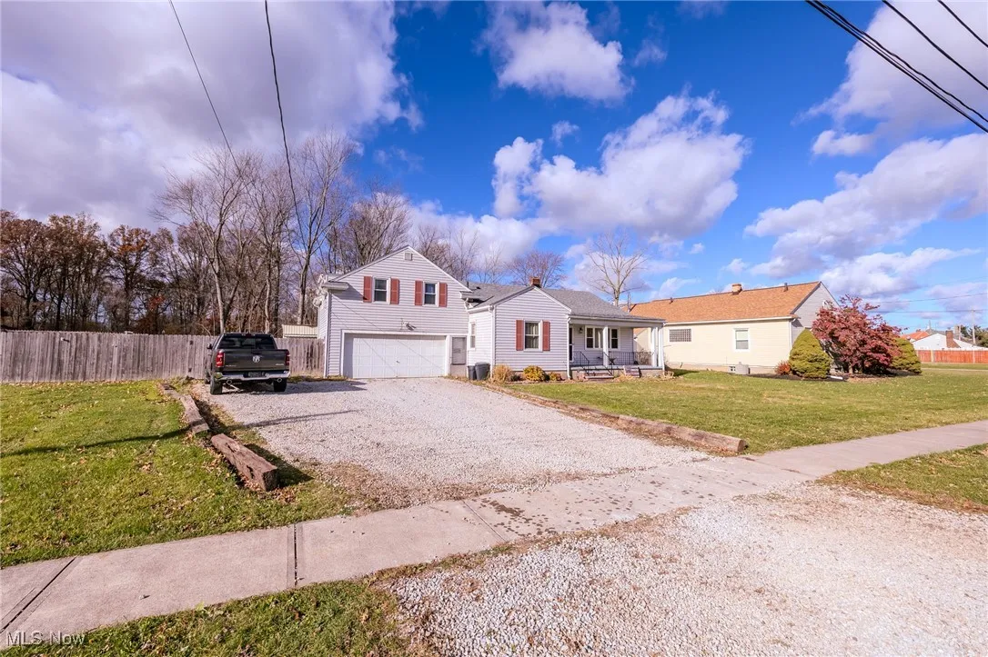 View of front facade with gravel driveway, a porch, and a garage