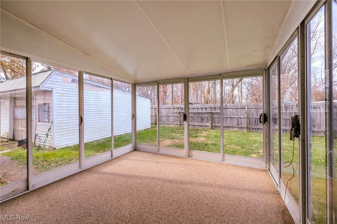 Unfurnished sunroom with healthy amount of natural light and vaulted ceiling