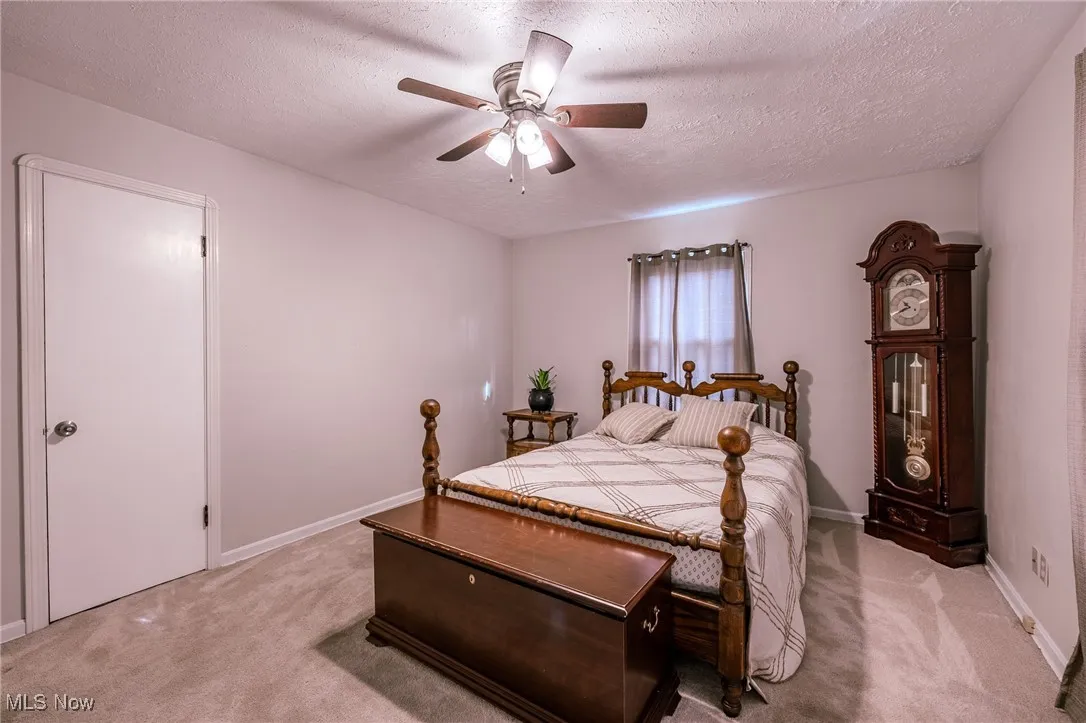 Bedroom with a textured ceiling, ceiling fan, and light carpet