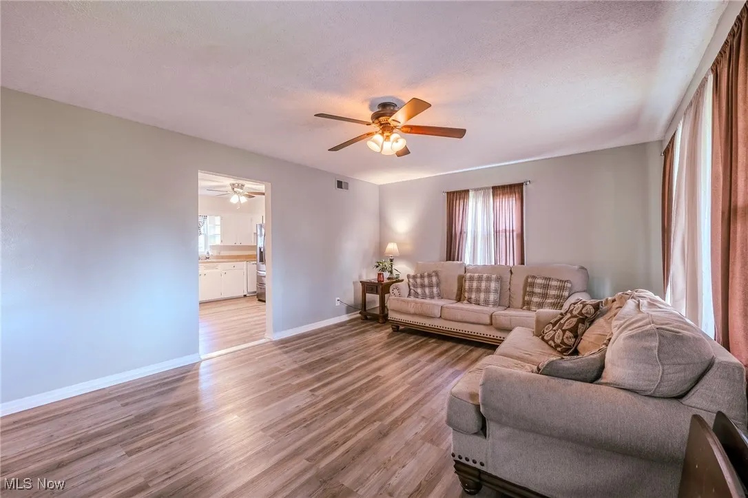 Living room with wood finished floors, a textured ceiling, and a ceiling fan