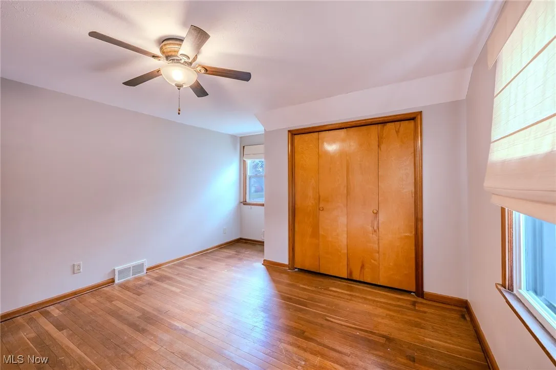 Unfurnished bedroom featuring hardwood / wood-style floors, a ceiling fan, and a closet