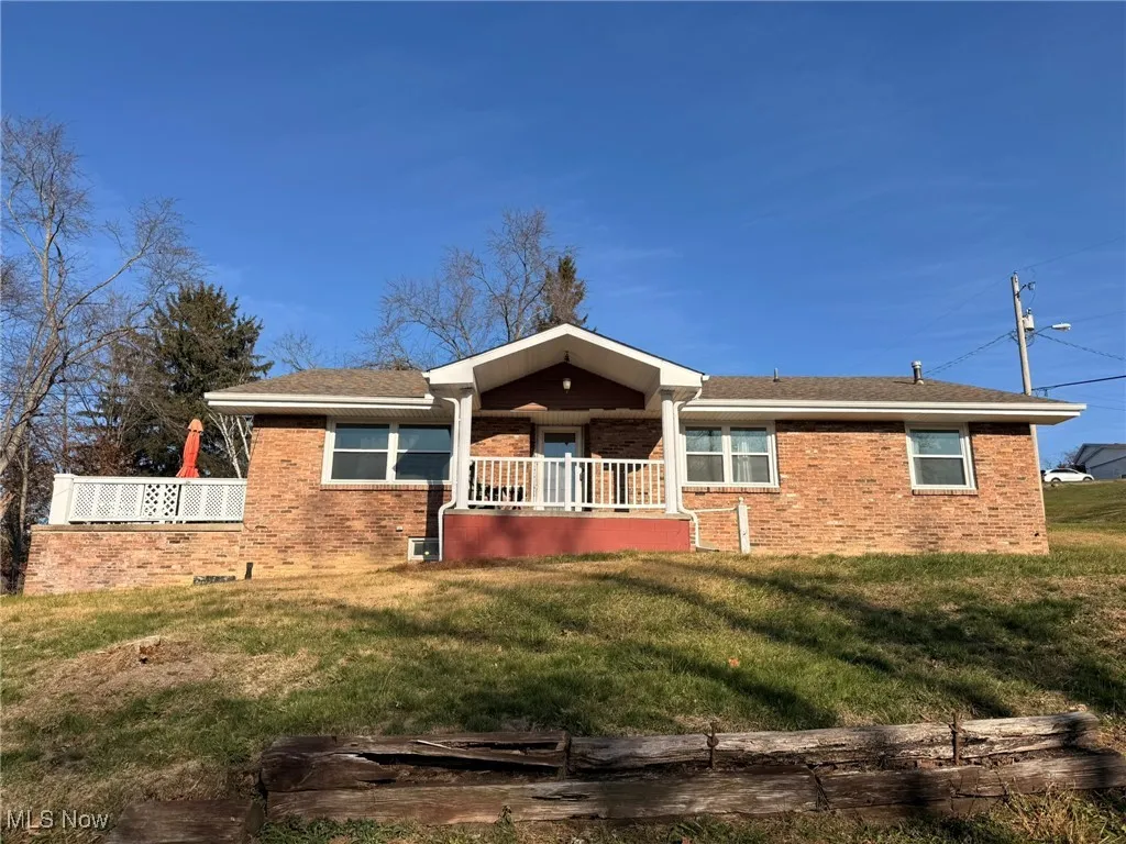 View of front of property featuring a front yard, brick siding, and a shingled roof