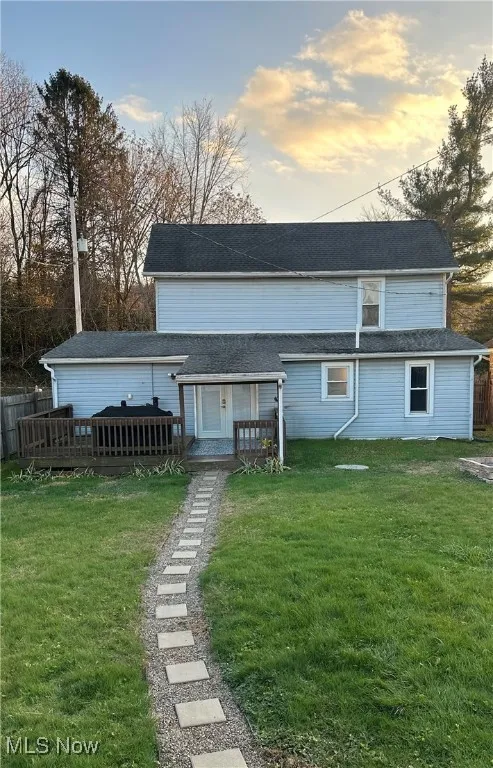 Back of house with a deck and a shingled roof