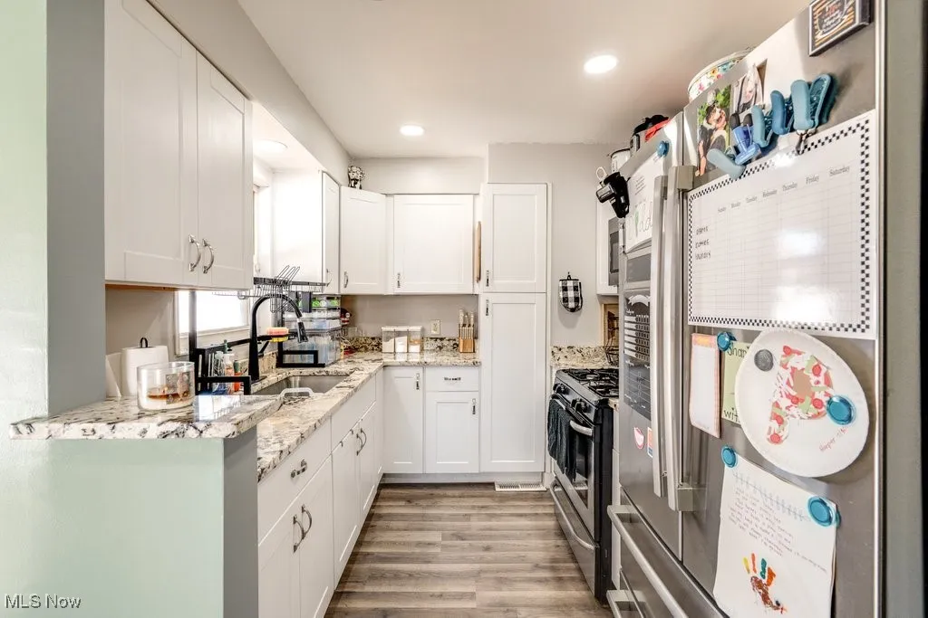 Kitchen featuring white cabinets, granite countertops, and ss appliances