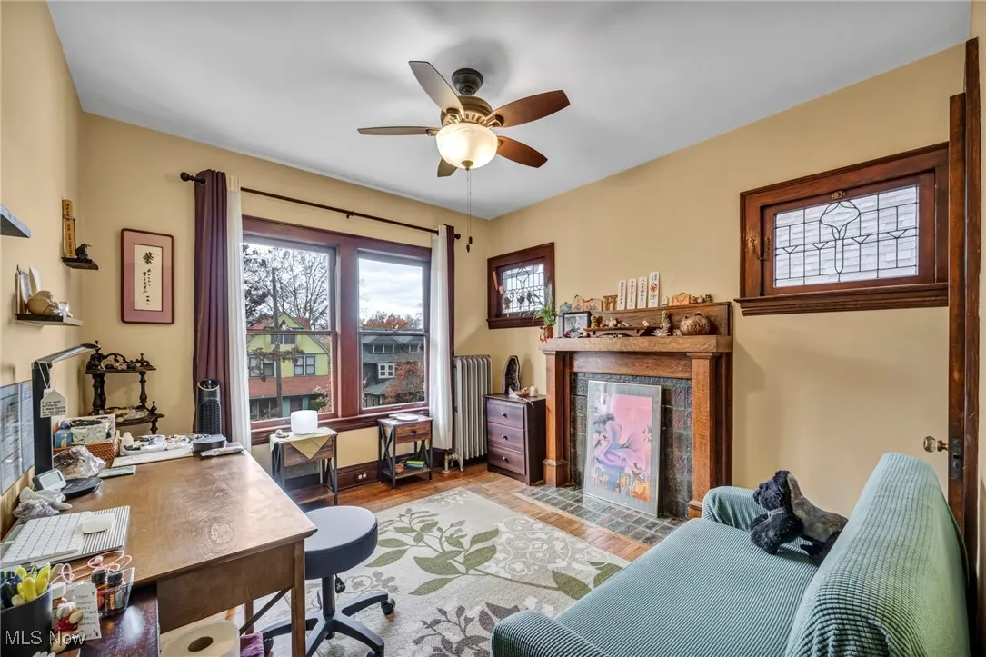 Home office with a tile fireplace, radiator heating unit, wood finished floors, and ceiling fan