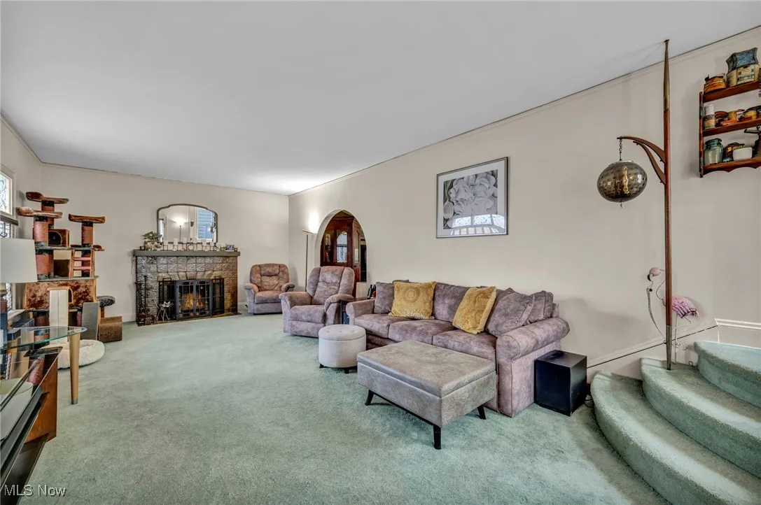 Living room featuring carpet flooring, a fireplace, and arched walkways