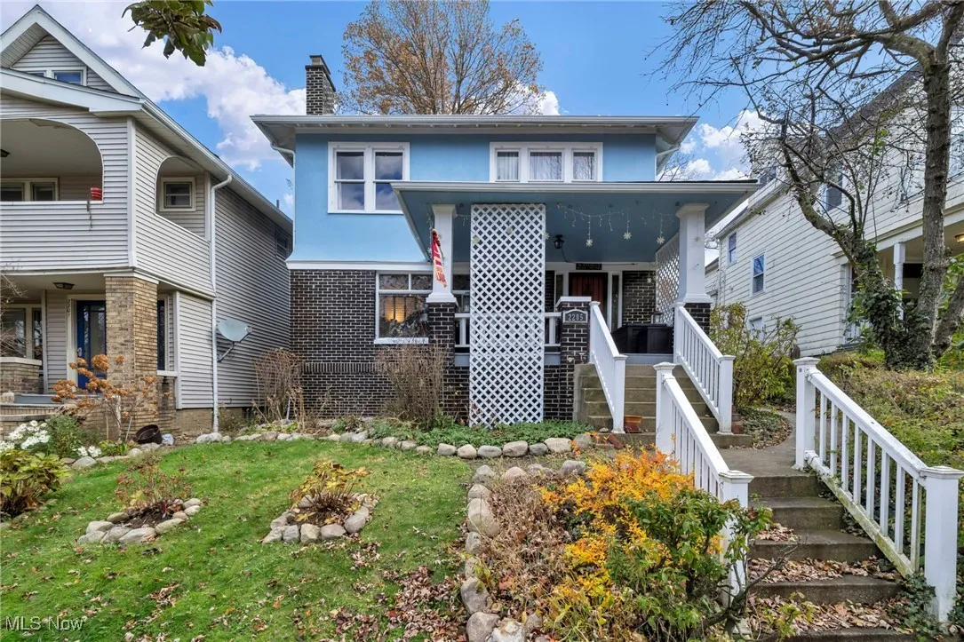 View of front of house with stairway, a chimney, brick siding, a fire pit, and a porch