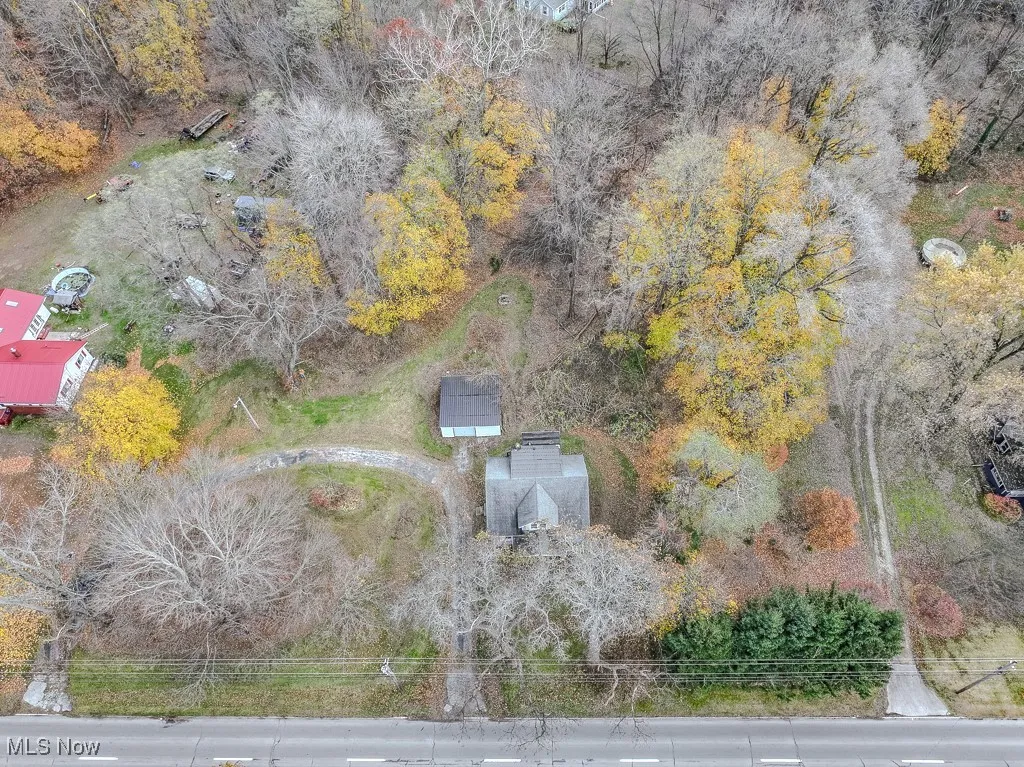 Aerial of horseshoe driveway, house, garage, and wooded part of the property