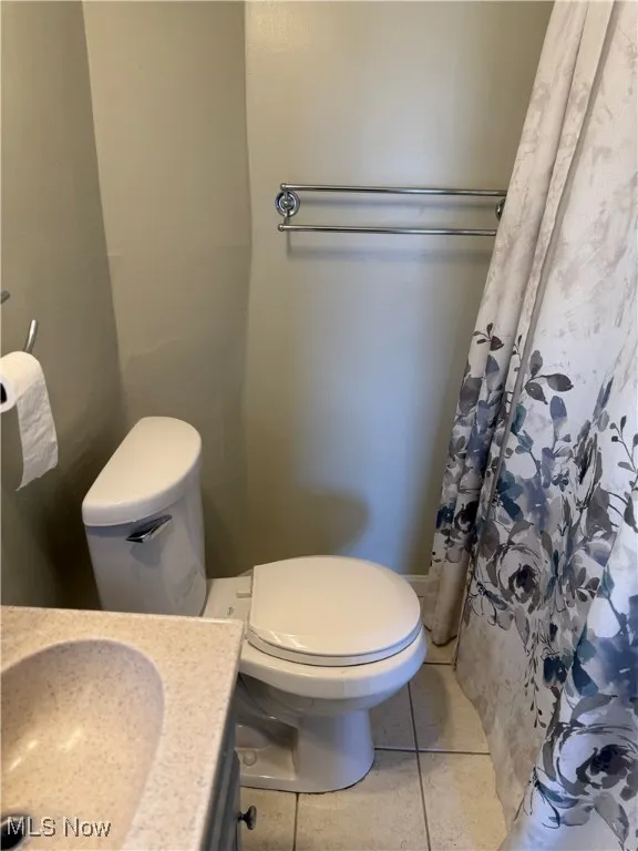 Bathroom featuring curtained shower, tile patterned floors, and vanity
