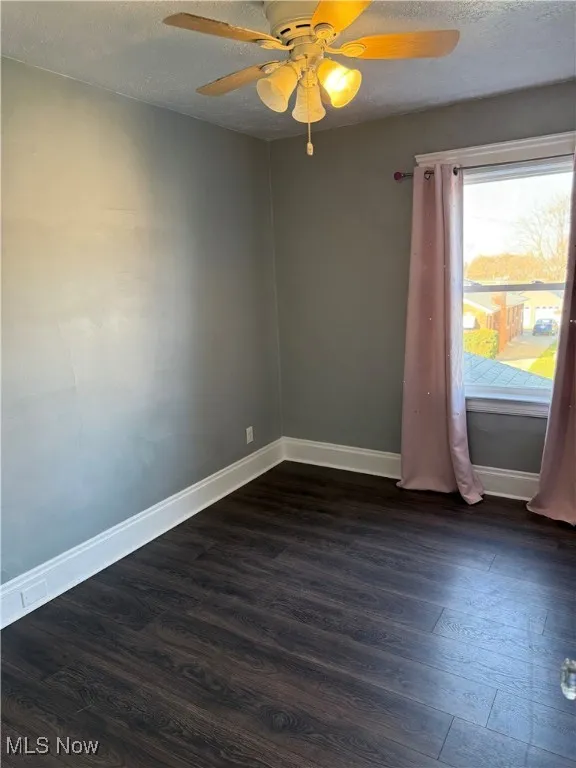 Unfurnished room with dark wood-type flooring, a textured ceiling, and ceiling fan