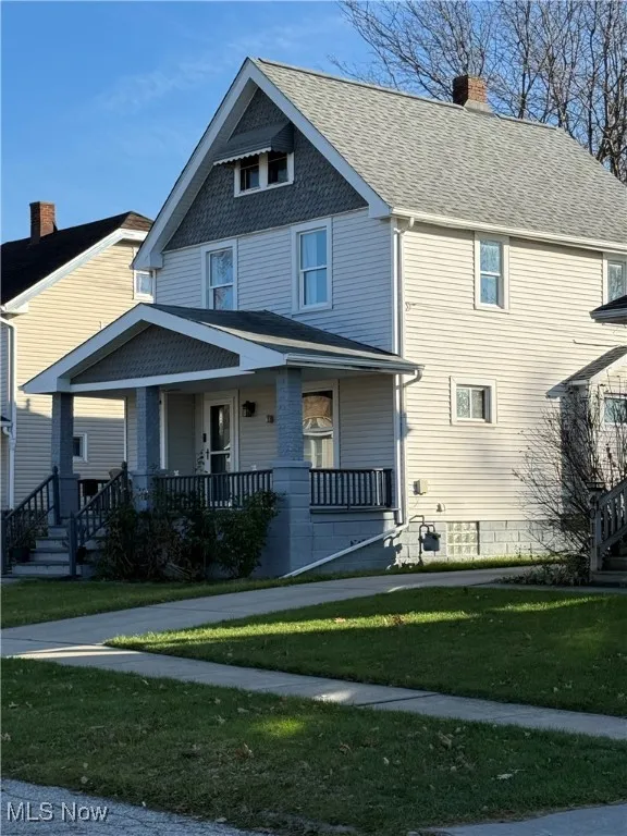 View of front of property with a porch, roof with shingles, a chimney, a front lawn, and stairway