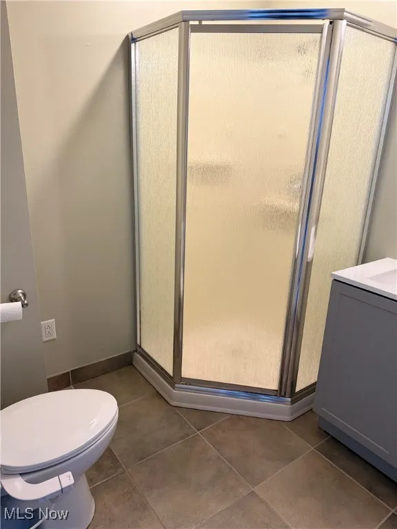 Bathroom featuring a stall shower, vanity, and dark tile patterned floors