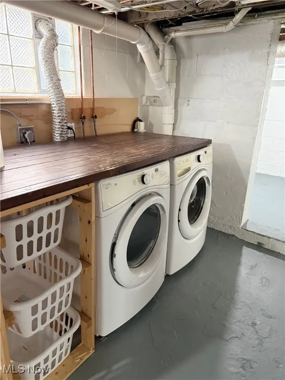 Washroom with concrete flooring and washer and clothes dryer