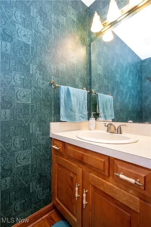Bathroom with wallpapered walls and vanity
