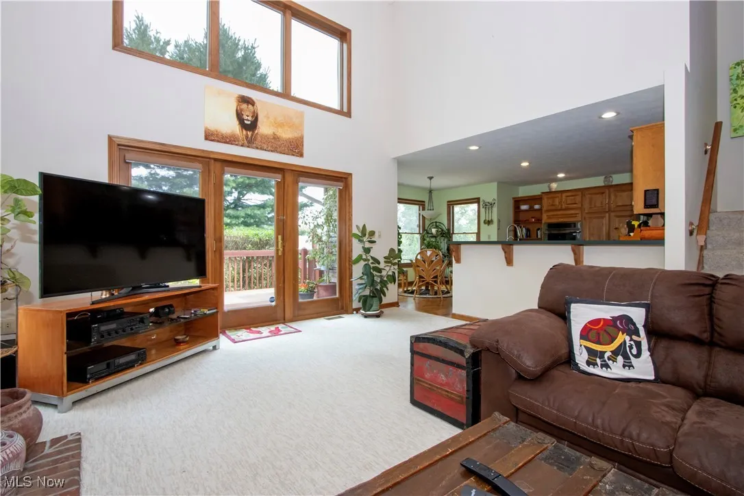 Living room featuring light carpet, a towering ceiling, and recessed lighting