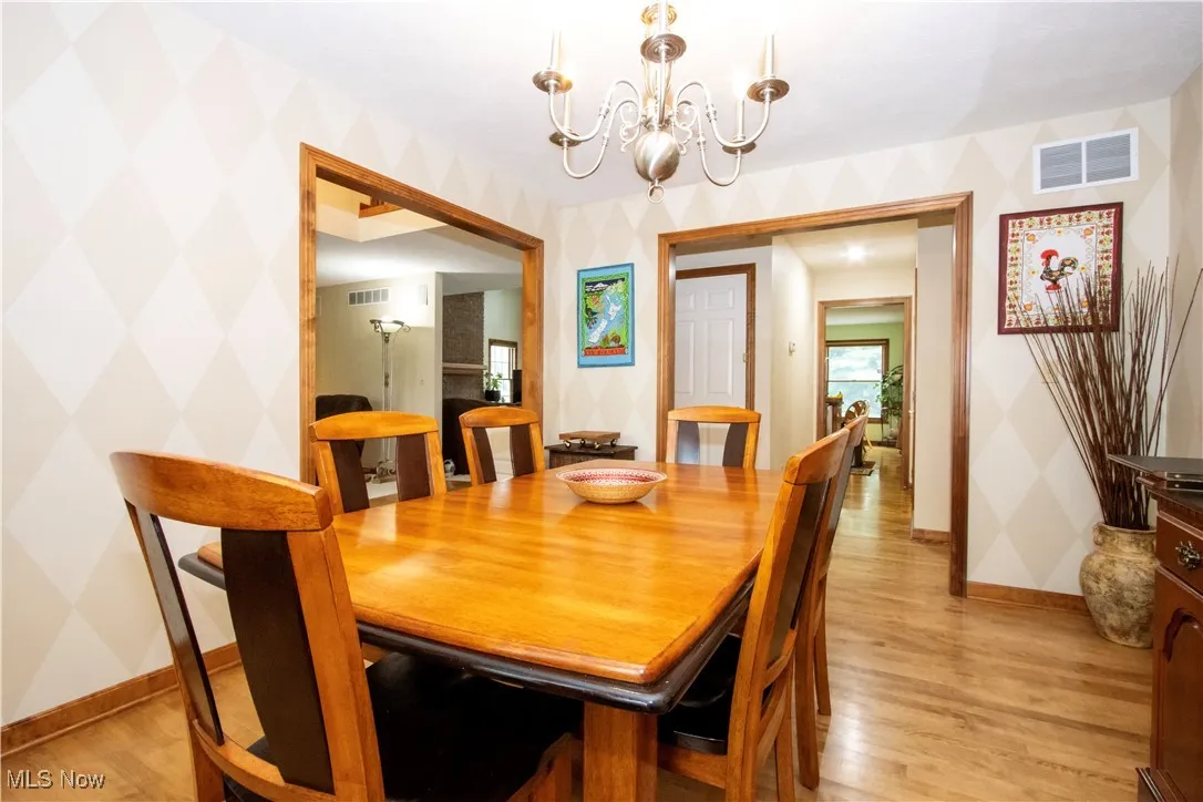 Dining space featuring wallpapered walls, a chandelier, and light wood finished floors