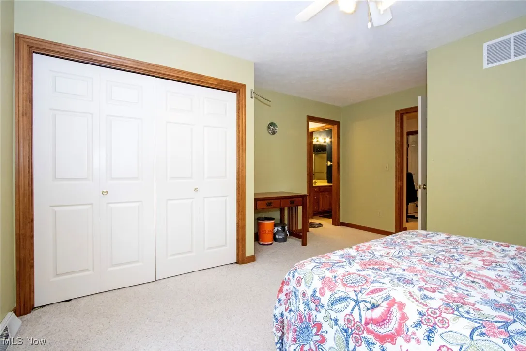 Bedroom with carpet floors, a closet, ceiling fan, and connected bathroom