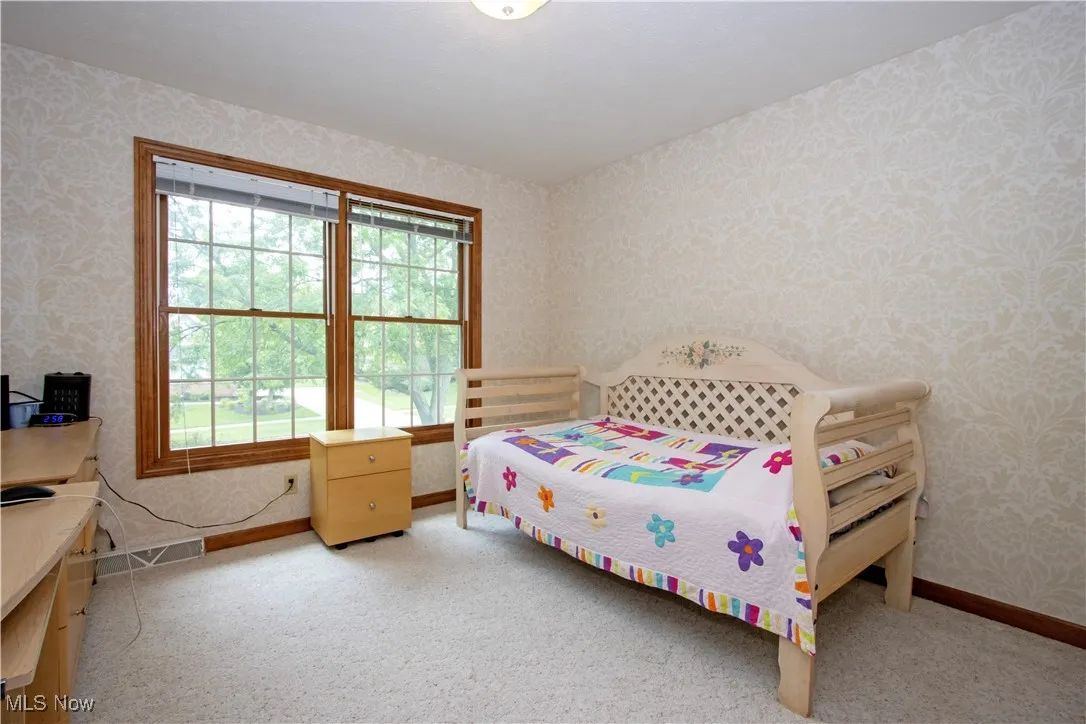 Bedroom with wallpapered walls and carpet