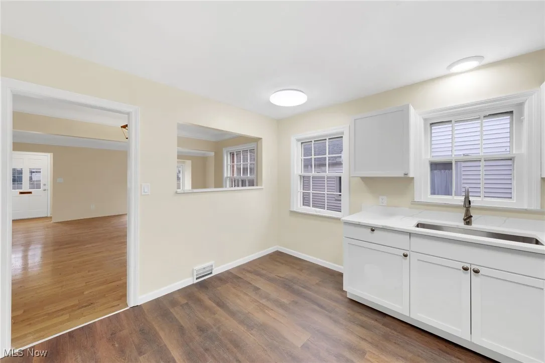 Kitchen featuring white cabinetry, dark wood finished floors, and light stone counters