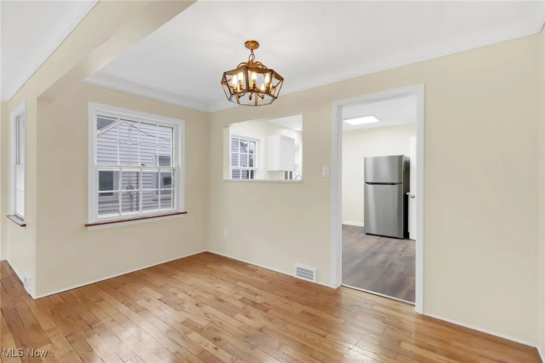 Unfurnished dining area with a chandelier and light wood-style floors