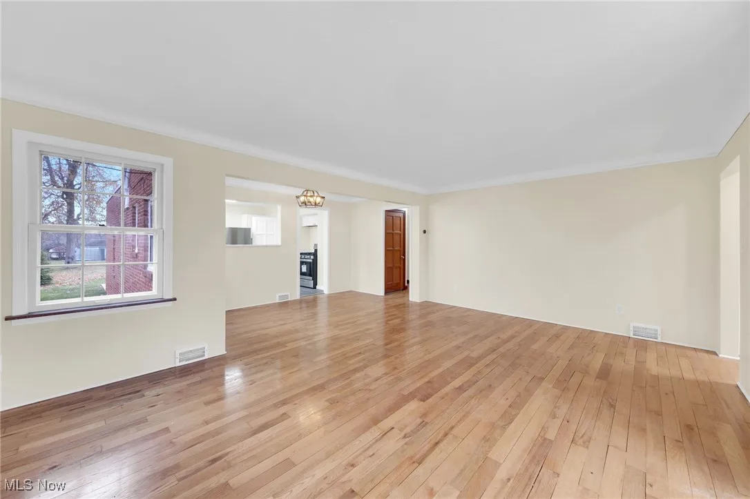 Unfurnished living room with light wood finished floors and crown molding