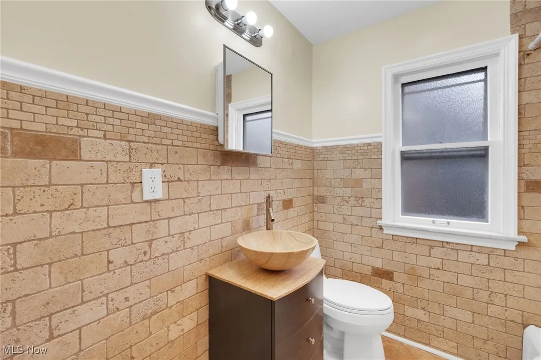Bathroom featuring a wainscoted wall, vanity, and tile walls