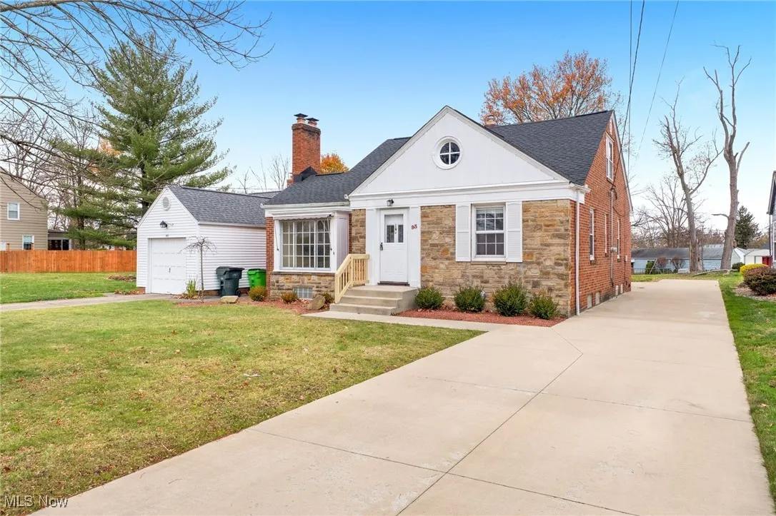 View of front of house featuring stone siding, a chimney, driveway, a garage, and a shingled roof
