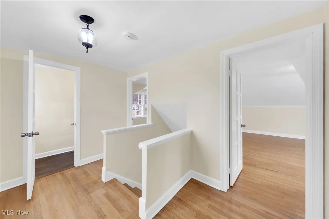 Corridor with an upstairs landing and light wood-style floors