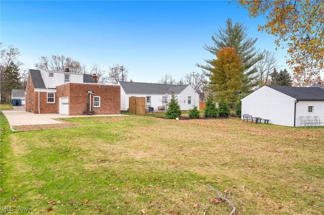 Rear view of house featuring a lawn, brick siding, a garage, and a patio area