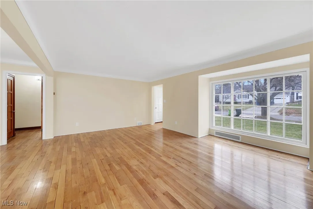 Spare room with light wood-type flooring and crown molding