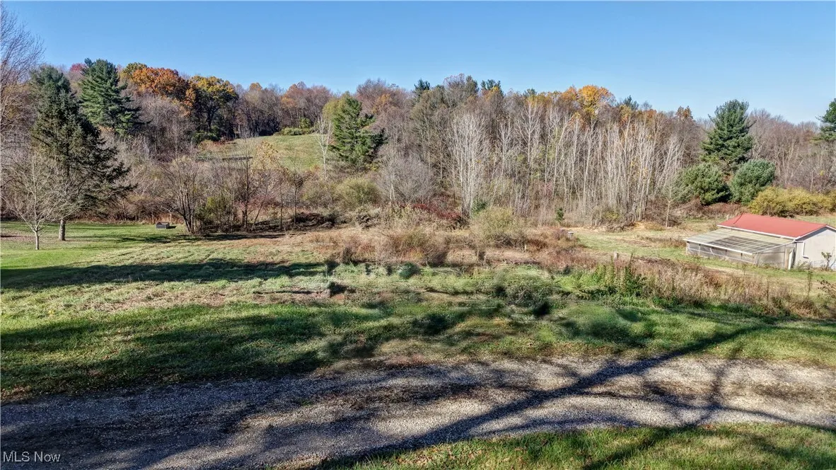 View of green lawn featuring an outbuilding, a wooded view, a view of countryside, and a greenhouse