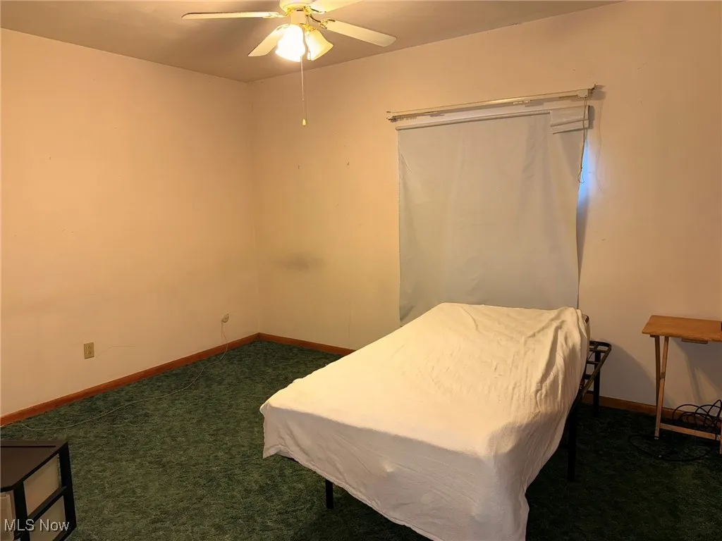 Bedroom with dark colored carpet and a ceiling fan