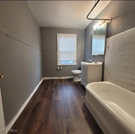 Full bathroom featuring a tub to relax in, vanity, and dark wood-style flooring