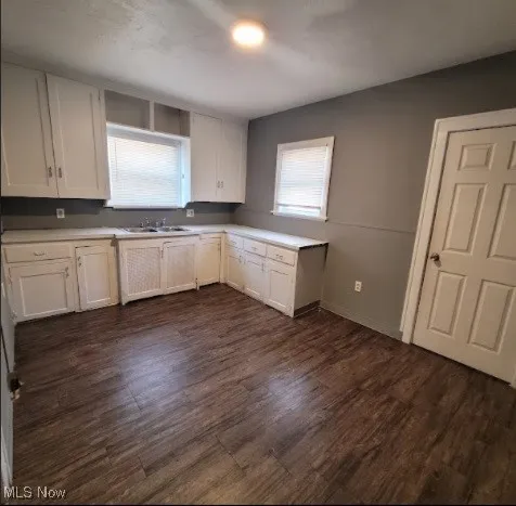 Kitchen with white cabinets, light countertops, and dark wood-style floors