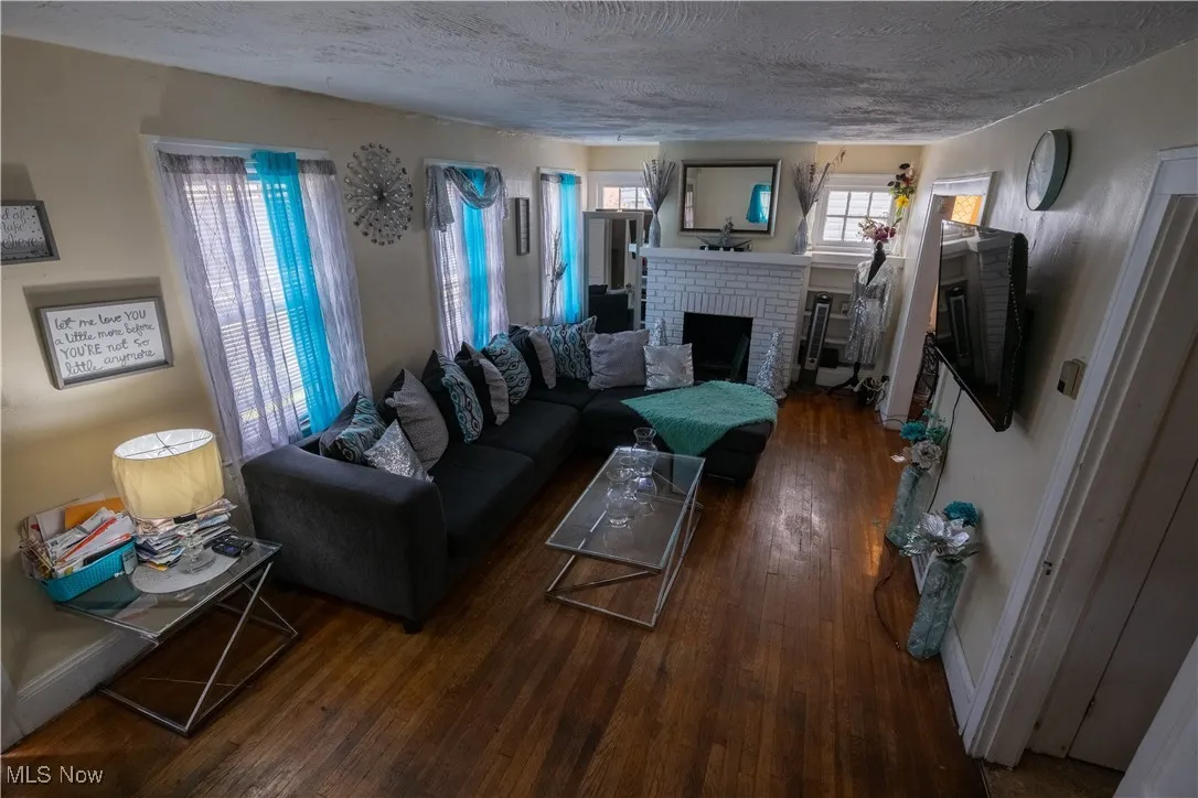 Living area with a brick fireplace, hardwood / wood-style floors, and a textured ceiling