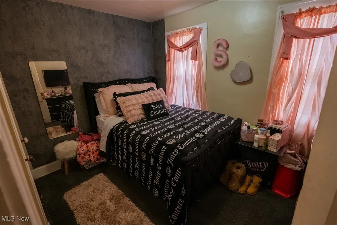 Bedroom with dark colored carpet and baseboards