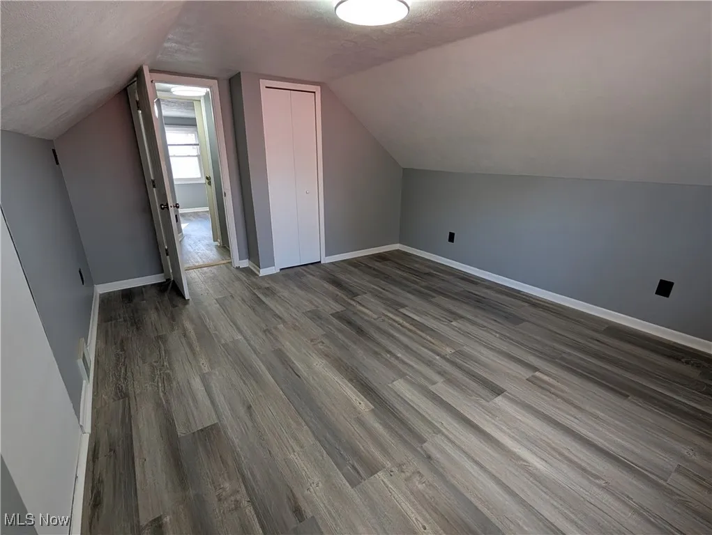 Upper level Bedroom with a textured ceiling, lofted ceiling, and wood finished floors